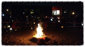 Kinder mit bunten Laternen versammeln sich vor einem Martinsfeuer.