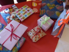 Bunt eingepackte Geschenke auf einem Tisch mit roter Tischdecke.